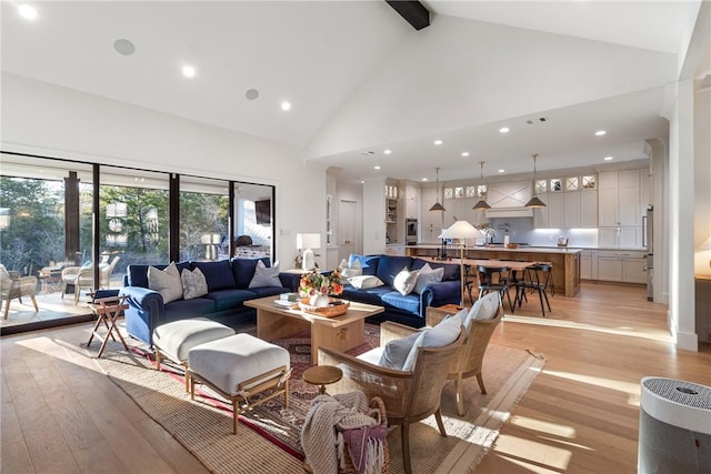 living area with light wood-type flooring, high vaulted ceiling, beam ceiling, and recessed lighting