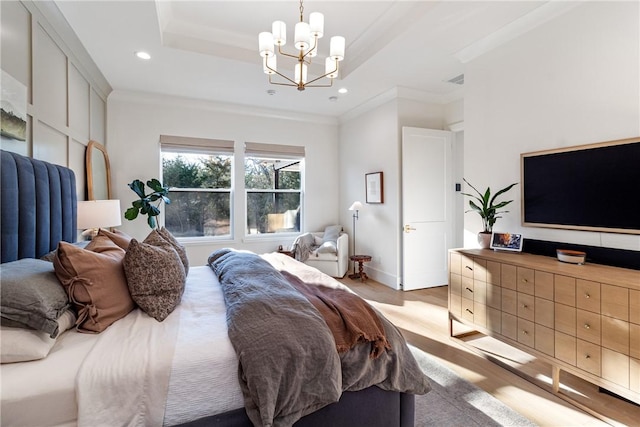 bedroom with light wood-style flooring, ornamental molding, a tray ceiling, a chandelier, and recessed lighting