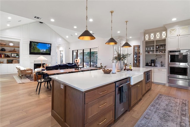 kitchen with glass insert cabinets, stainless steel appliances, light countertops, white cabinetry, and pendant lighting