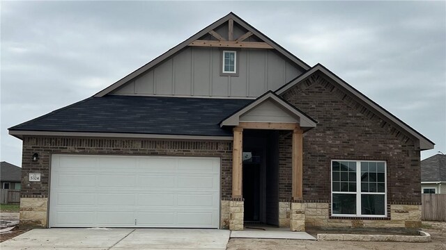 5324 Lyle Pl, Bryan, TX 77807 - view of front of house with board and batten siding, driveway, a garage, brick siding, and stone siding