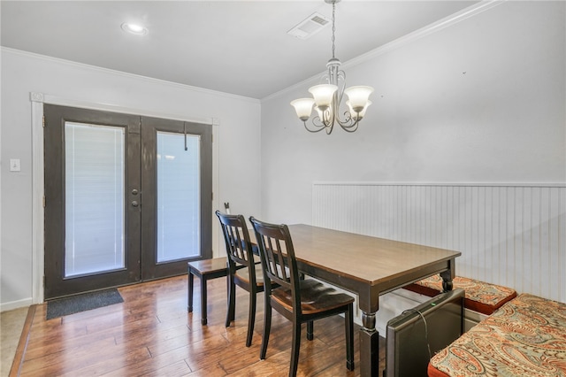 dining room featuring crown molding, french doors, wood-type flooring, and an inviting chandelier