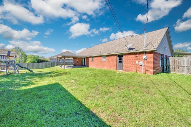 rear view of house with a playground, a yard, and a patio