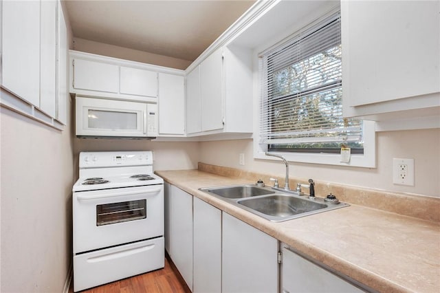 kitchen featuring light countertops, light wood-style flooring, white cabinets, a sink, and white appliances