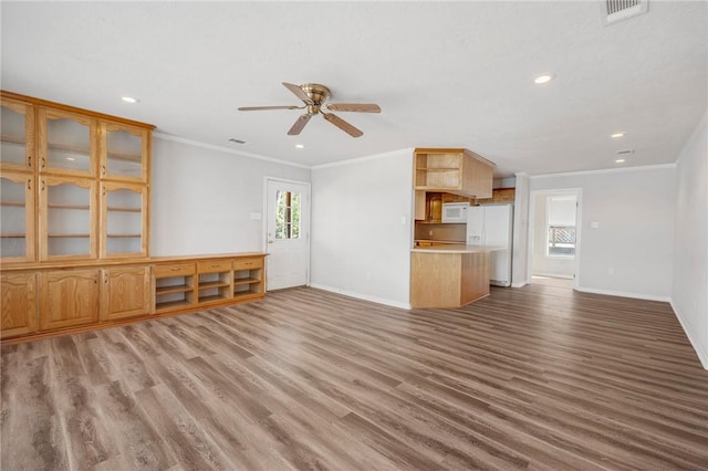 unfurnished living room featuring visible vents, crown molding, baseboards, and wood finished floors