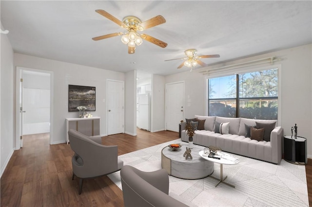 living room featuring a ceiling fan, baseboards, and wood finished floors