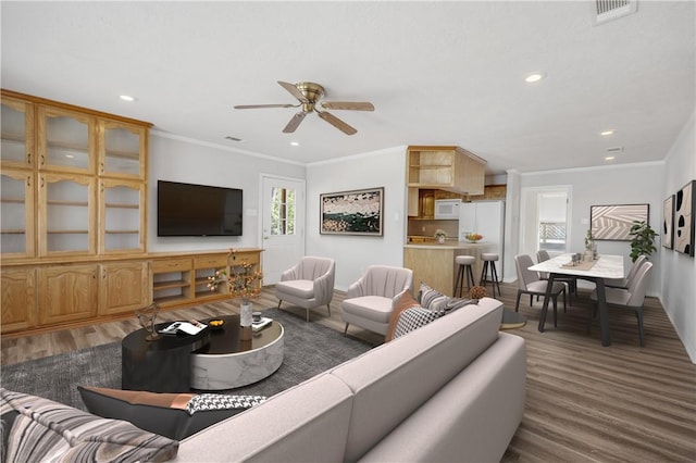 living room featuring recessed lighting, visible vents, wood finished floors, and ornamental molding