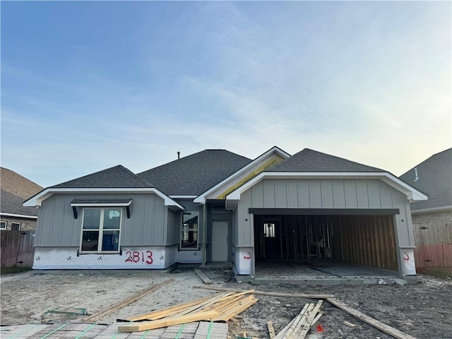 property in mid-construction featuring fence, roof with shingles, board and batten siding, and a garage