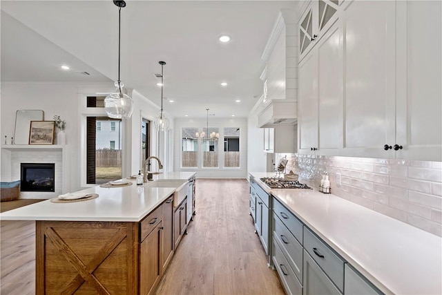 kitchen featuring pendant lighting, crown molding, white cabinetry, backsplash, and stainless steel gas stovetop