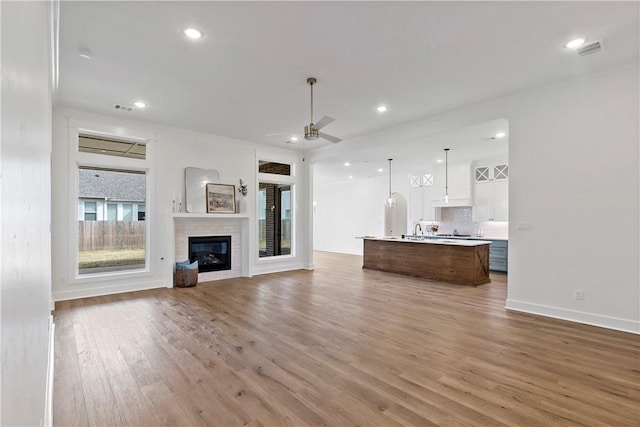 unfurnished living room featuring sink, wood-type flooring, and ceiling fan