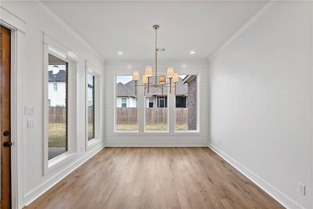 unfurnished dining area featuring ornamental molding, a chandelier, and light wood-type flooring