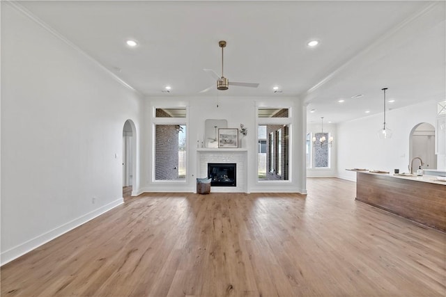 unfurnished living room with sink, ornamental molding, light hardwood / wood-style floors, and ceiling fan