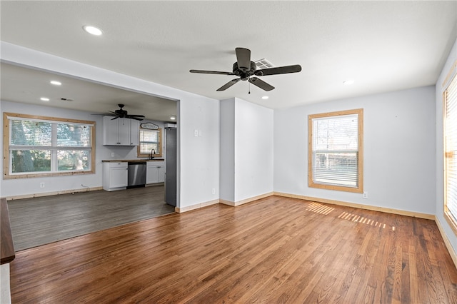 unfurnished living room with ceiling fan, hardwood / wood-style floors, and sink