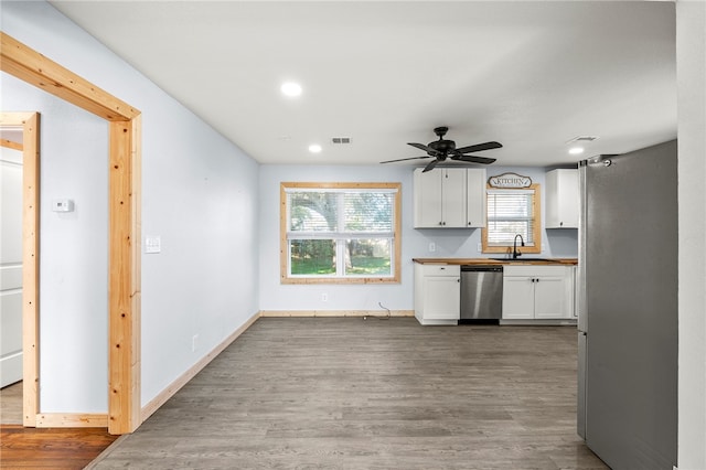 kitchen featuring appliances with stainless steel finishes, dark hardwood / wood-style flooring, ceiling fan, sink, and white cabinetry