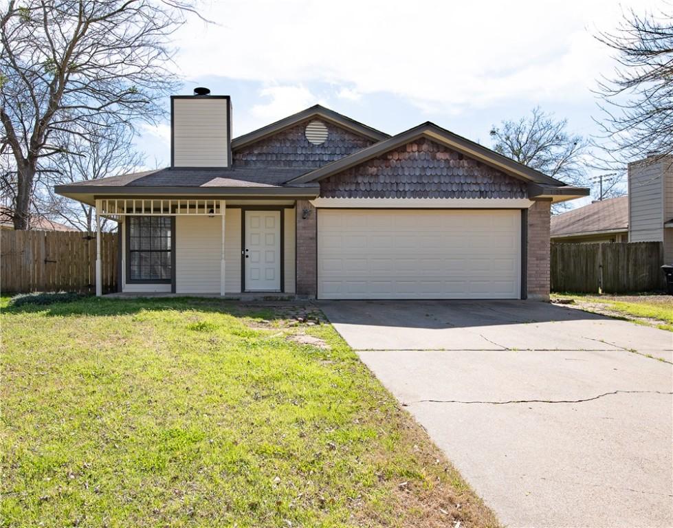 view of front of house featuring a chimney, concrete driveway, fence, a garage, and a front lawn