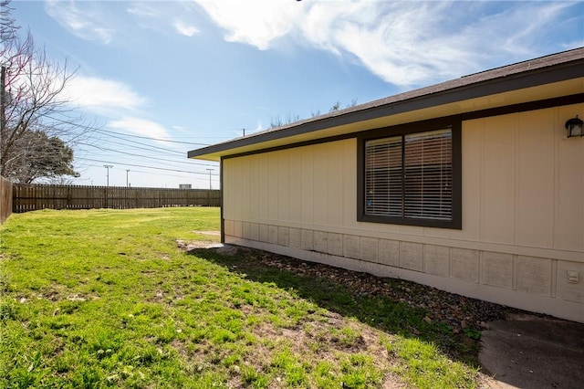 view of side of property with a lawn and fence