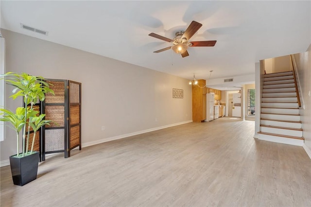 unfurnished living room with light wood-type flooring and ceiling fan with notable chandelier