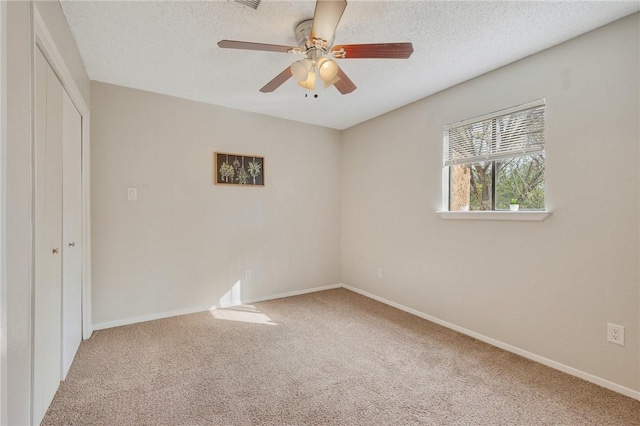 unfurnished bedroom featuring ceiling fan, carpet floors, a textured ceiling, and a closet