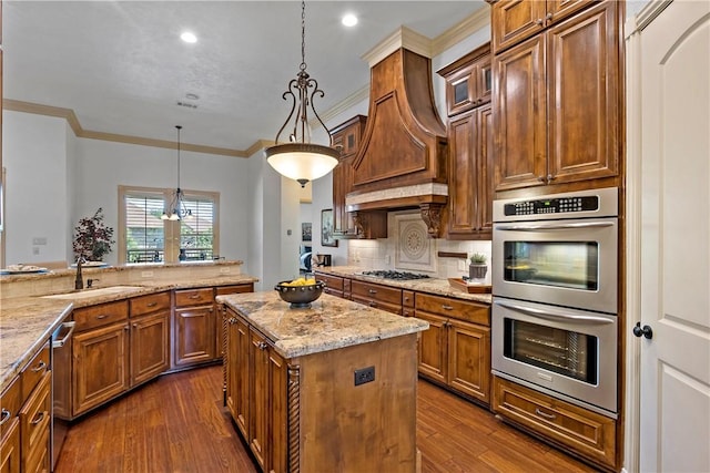 kitchen with stainless steel appliances, a sink, brown cabinetry, light stone countertops, and dark wood-style floors