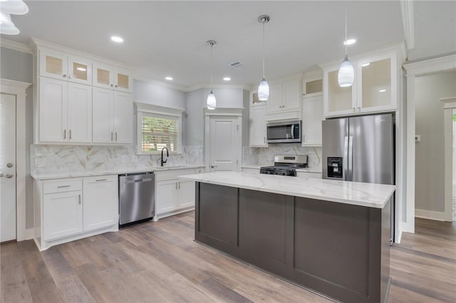 1410 Rochester St, Bryan, TX 77803 - kitchen with appliances with stainless steel finishes, a center island, white cabinetry, backsplash, and ornamental molding