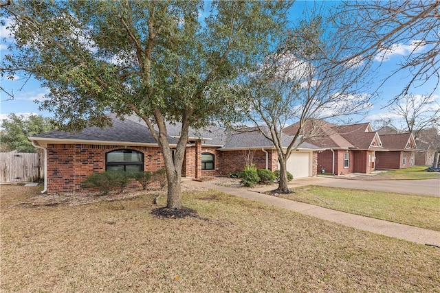 ranch-style home featuring brick siding, a front lawn, fence, a garage, and driveway