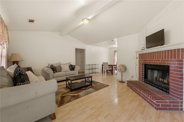 living room featuring lofted ceiling with beams, light hardwood / wood-style floors, and a fireplace