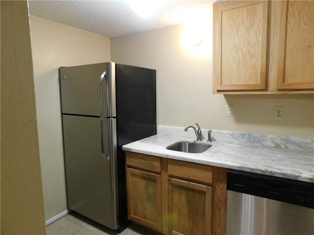 kitchen with light brown cabinets, sink, light tile patterned floors, a textured ceiling, and appliances with stainless steel finishes