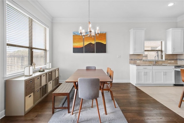 dining space featuring crown molding, sink, wood-type flooring, and an inviting chandelier