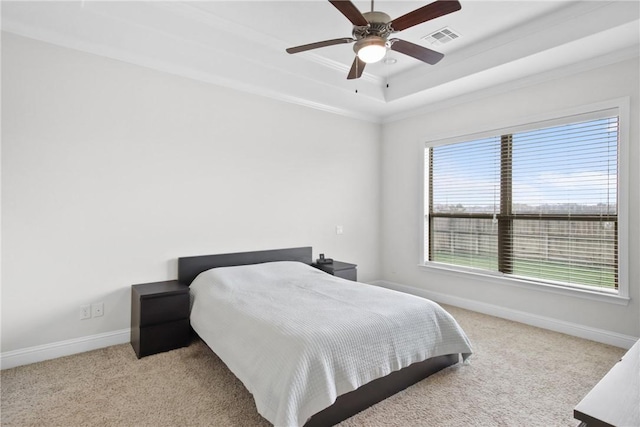 carpeted bedroom with ceiling fan, a raised ceiling, and ornamental molding