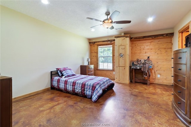 bedroom featuring wooden walls, ceiling fan, and a textured ceiling