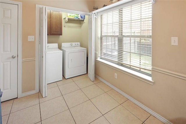 laundry room featuring washing machine and dryer, cabinets, and light tile patterned floors