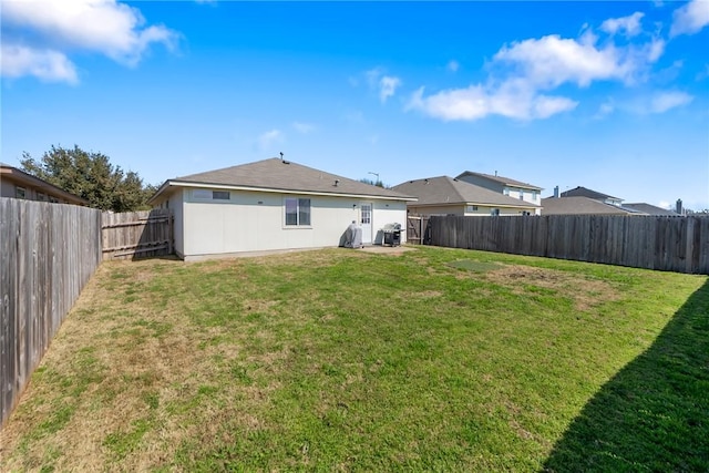 rear view of property featuring a yard and a fenced backyard