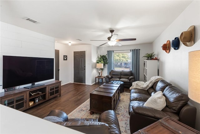 living area with dark wood-style floors, visible vents, baseboards, and ceiling fan