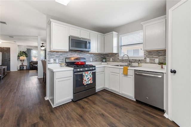 kitchen with backsplash, appliances with stainless steel finishes, light countertops, and a sink