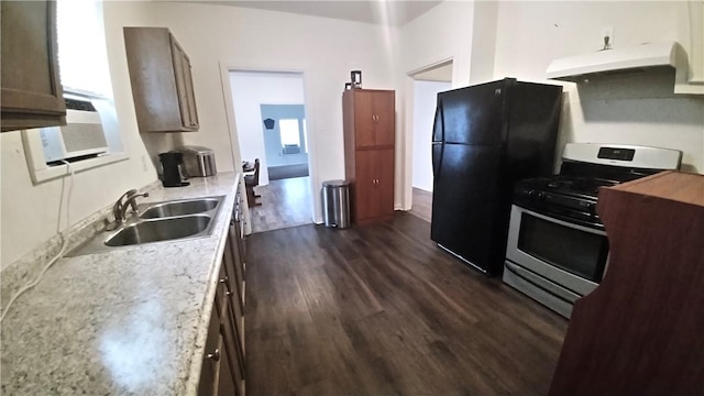 kitchen with dark wood-style floors, freestanding refrigerator, stainless steel range with gas cooktop, under cabinet range hood, and a sink