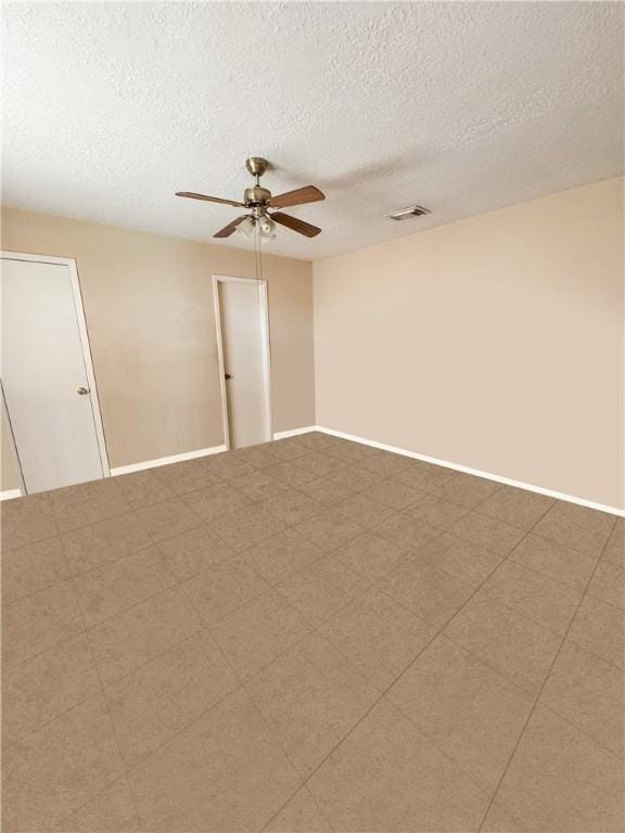 unfurnished room with visible vents, baseboards, tile patterned floors, a textured ceiling, and a ceiling fan