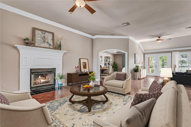 living room featuring ceiling fan, dark hardwood / wood-style flooring, ornamental molding, and a tiled fireplace