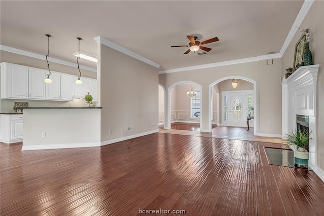 unfurnished living room with crown molding, wood-type flooring, and ceiling fan with notable chandelier