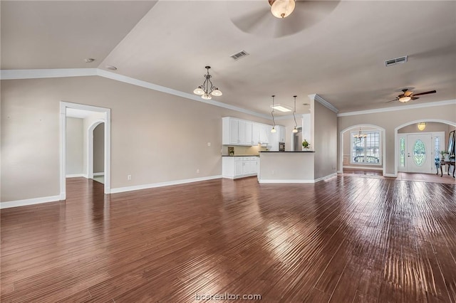 unfurnished living room featuring ceiling fan with notable chandelier, crown molding, and dark wood-type flooring