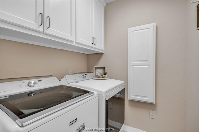 clothes washing area with cabinets and washing machine and clothes dryer