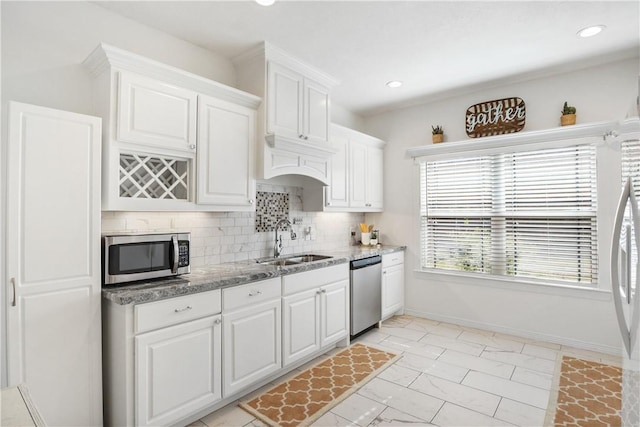 kitchen featuring stainless steel appliances, white cabinetry, sink, and backsplash