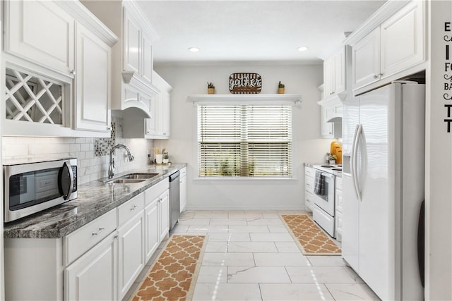 kitchen with white cabinetry, stainless steel appliances, sink, and dark stone counters