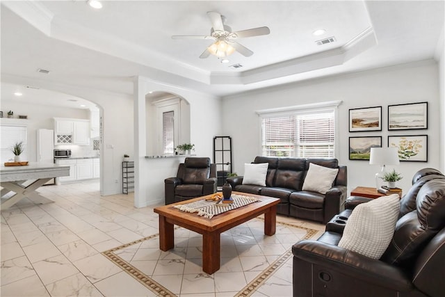 living room with crown molding, ceiling fan, and a tray ceiling