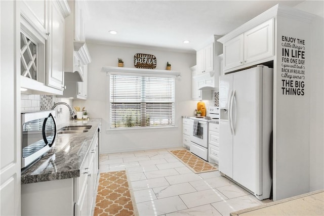 kitchen with white cabinetry, sink, backsplash, dark stone counters, and white appliances