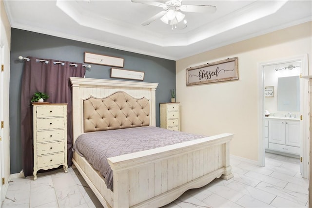 bedroom featuring ensuite bathroom, ornamental molding, ceiling fan, and a tray ceiling