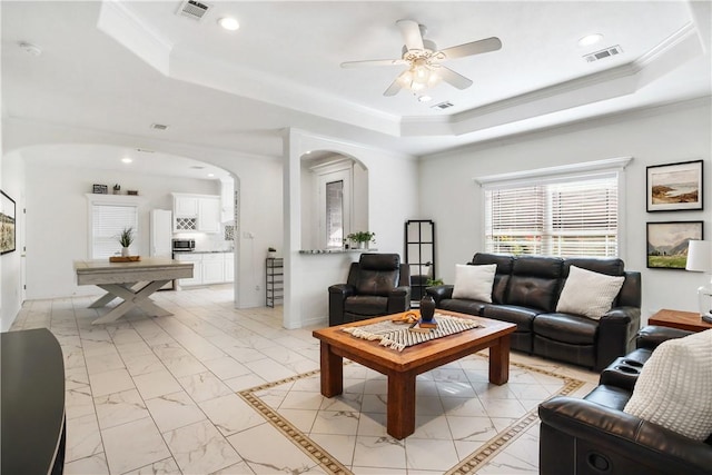 living room featuring ornamental molding, a raised ceiling, and ceiling fan