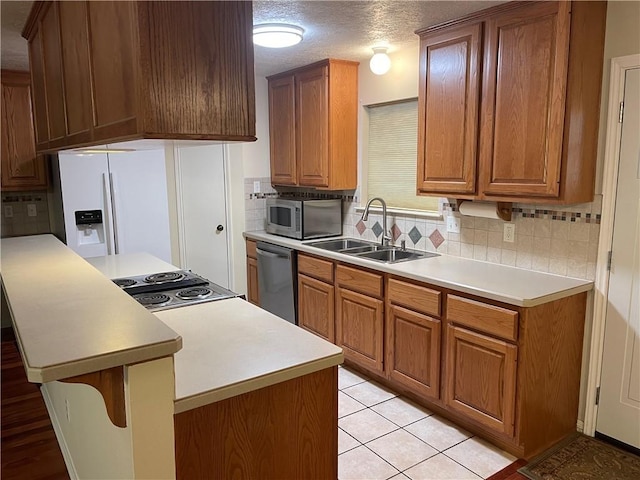 kitchen with appliances with stainless steel finishes, tasteful backsplash, a textured ceiling, sink, and light tile patterned flooring