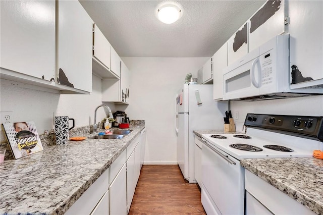 kitchen featuring a textured ceiling, wood finished floors, white appliances, white cabinetry, and a sink