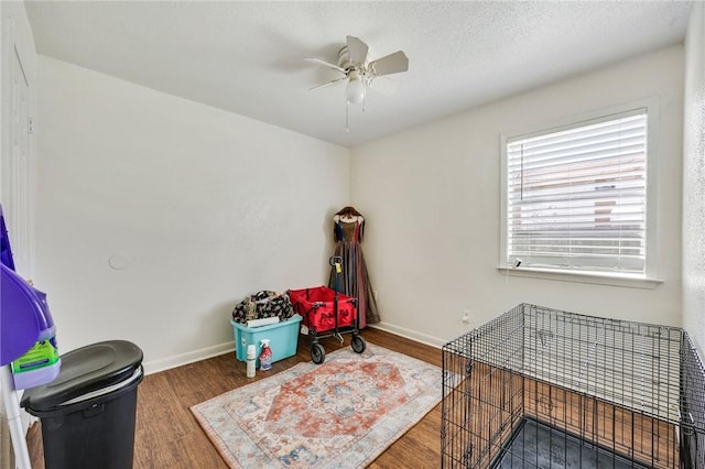 misc room featuring baseboards, a textured ceiling, wood finished floors, and a ceiling fan