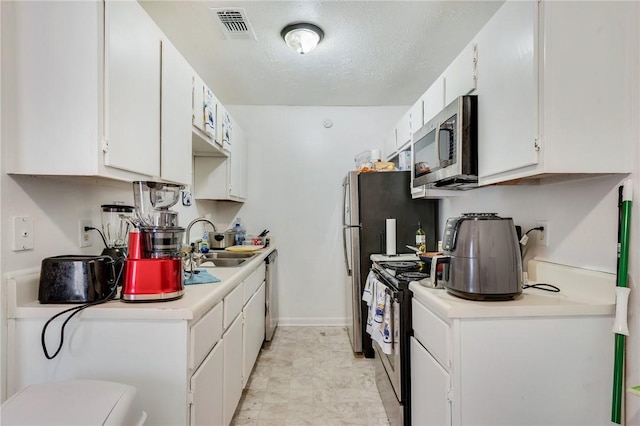 kitchen featuring visible vents, light countertops, white cabinets, stainless steel appliances, and a sink