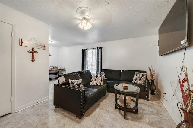 living area featuring ceiling fan, a textured ceiling, and baseboards